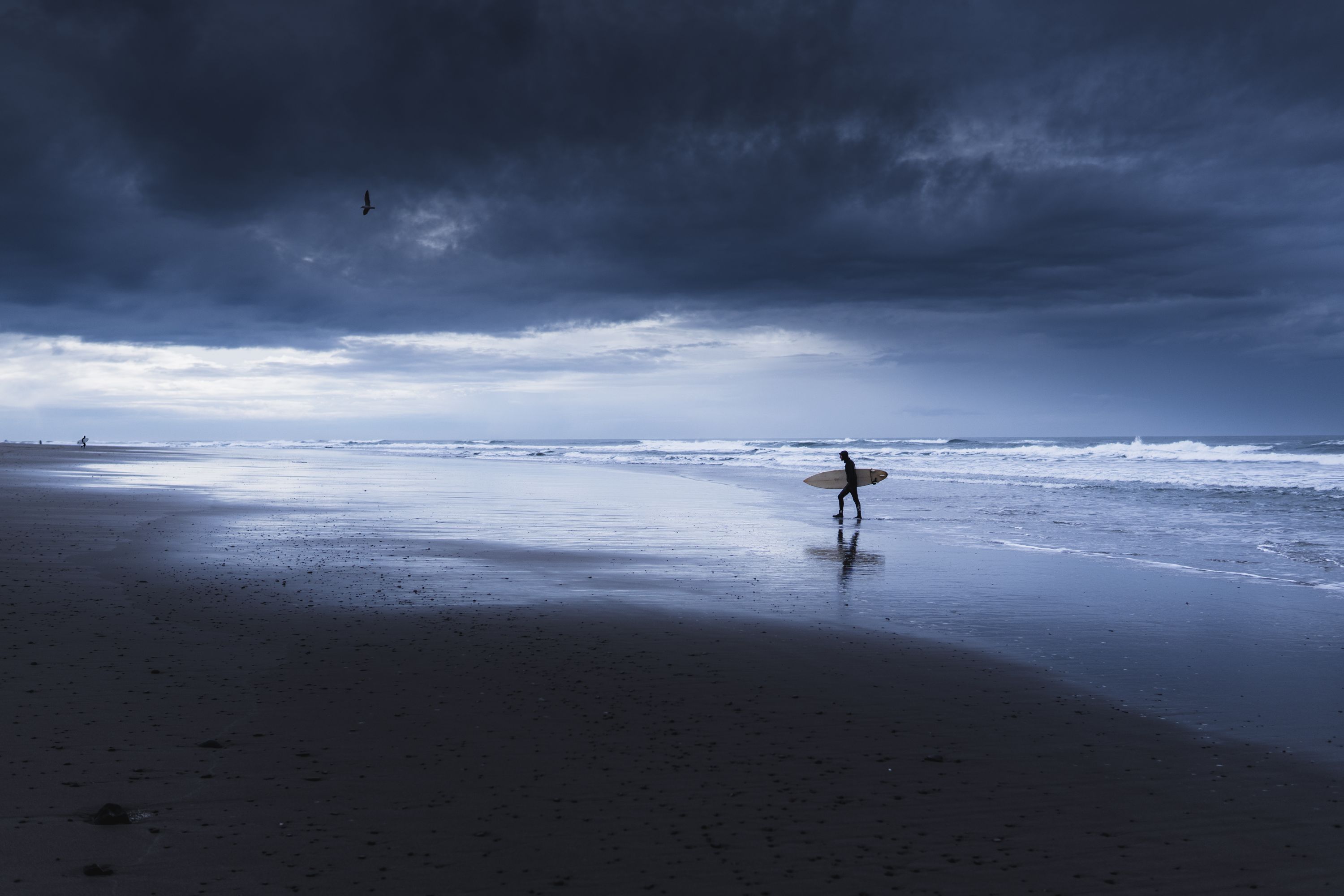 Surfero en una playa bajo nubes de tormenta