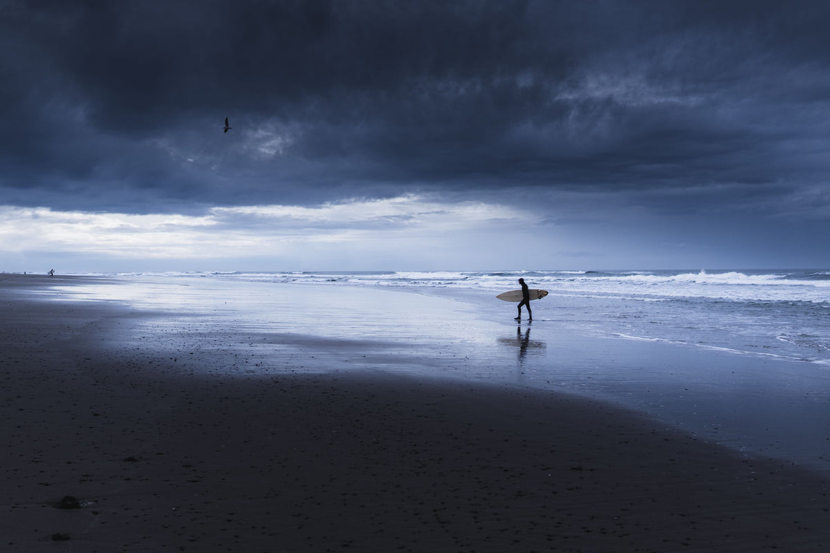 Surfero en una playa bajo nubes de tormenta