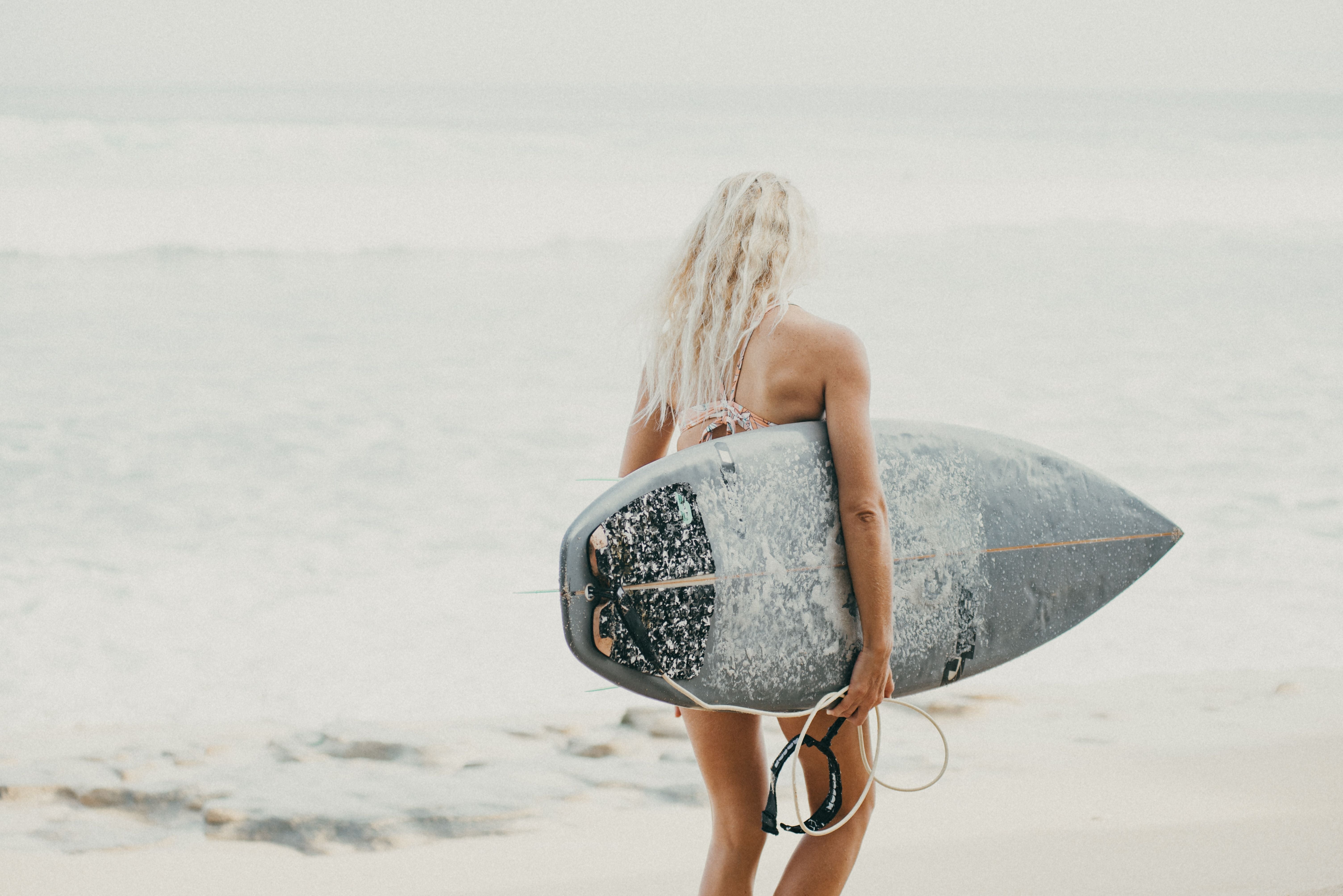Surfista de espaldas caminando hacia el mar con su tabla de surf