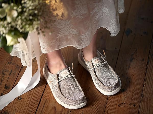 mujer cambiando tacones por zapatillas HEY DUDE en boda para bailar cómoda