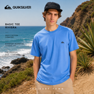 Camiseta Quiksilver Basic Tee Riviera en fotografía editorial propia de THE SURF TOWN junto al océano, camiseta básica surf de hombre en color azul Riviera con logo frontal y estilo veraniego premium.