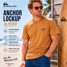 Camiseta Quiksilver Anchor Lockup Almond hombre en campaña lifestyle surf premium junto a tabla de surf y beach house soleada