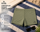 Bañador de natación Rip Curl Corp Boyleg Sluggo Surplus Green sobre toalla de playa en escena surf lifestyle premium
