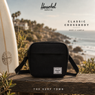 Bandolera Herschel Classic Crossbody Black en fotografía editorial propia de THE SURF TOWN con escenario coastal premium y estilo surf travel lifestyle