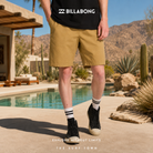 Bermudas Billabong Larry Linen Khaki para hombre en oasis de Arizona con fotografía editorial propia de THE SURF TOWN, estilo surf lifestyle premium y arquitectura desértica de lujo