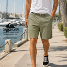 Bermudas Quiksilver Híbrido Union 19 Heather Grape Leaf en paseo marítimo junto a marina deportiva, fotografía editorial propia de THE SURF TOWN, short híbrido de secado rápido para playa, viajes y surf lifestyle premium.