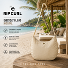 Bolso Rip Curl Everyday 8L Natural en fotografía editorial propia de THE SURF TOWN en beach club tropical premium con diseño ligero, gran capacidad y estilo surf femenino para playa, viajes y uso diario.