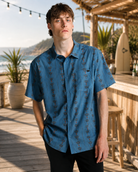Camisa Billabong Surftrek Perf Mid Blue para hombre en paseo marítimo junto a la playa con estilo surf lifestyle y ambiente Costa del Sol