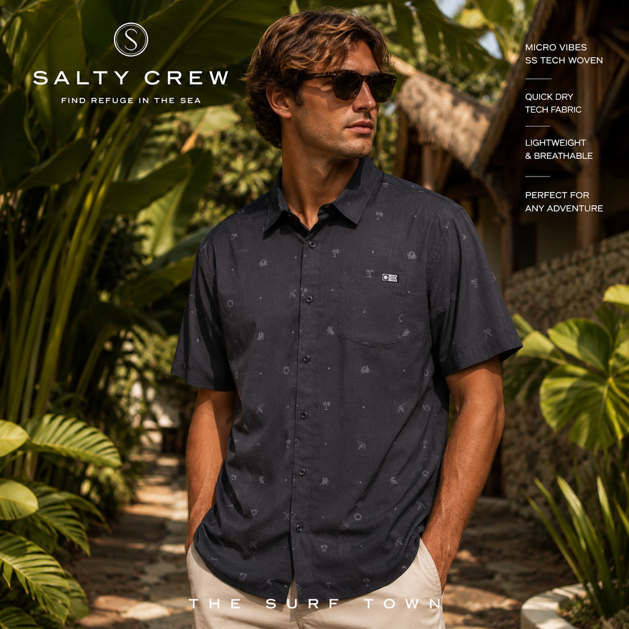 Camisa Salty Crew Micro Vibes SS Tech Woven Coal en jardín tropical de resort, fotografía editorial propia de THE SURF TOWN con modelo surf lifestyle, tejido técnico ligero y estilo premium para verano