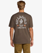Camiseta Billabong Coiled Premium Brown para hombre en color marrón con pequeño logo en el pecho y gran estampado trasero estilo surf vintage.