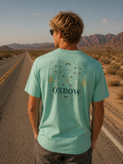Camiseta Oxbow Tekova Perfect Sky verde agua hombre con gráfica trasera en carretera desértica y estética editorial cinematográfica roadtrip