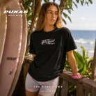 Camiseta Pukas Resin Black en fotografía editorial propia de THE SURF TOWN con estilo surf femenino, diseño minimalista y look lifestyle premium junto al mar