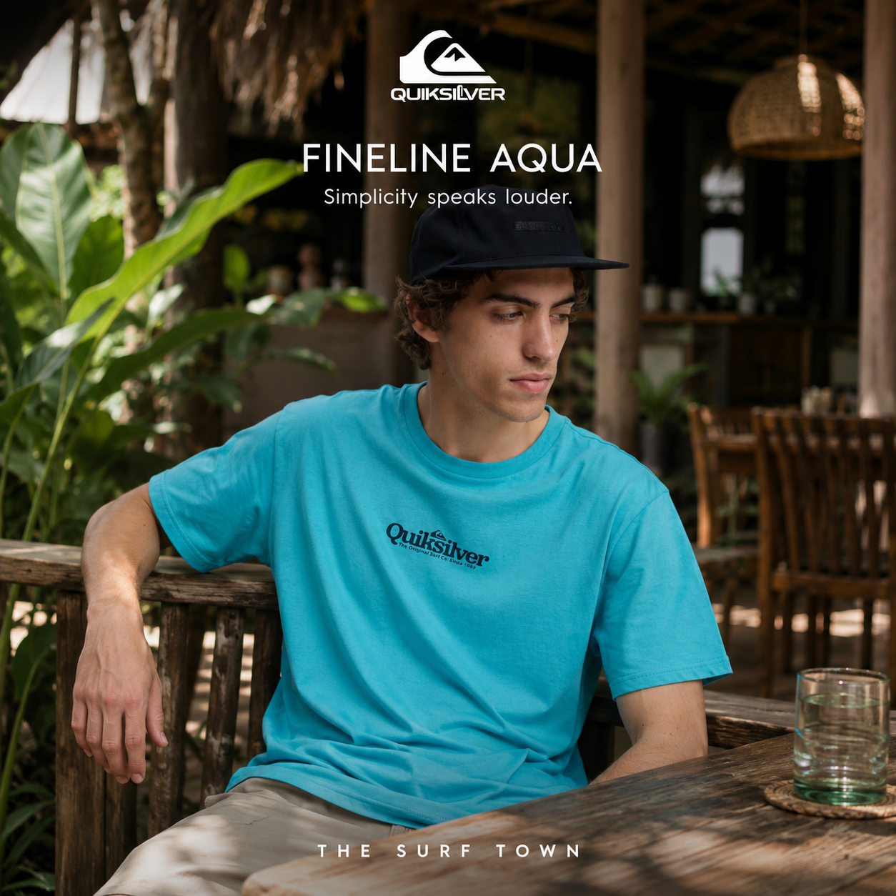 Camiseta Quiksilver Fineline Aqua en fotografía editorial propia de THE SURF TOWN en café tropical lifestyle con ambiente surf premium
