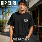 Camiseta Rip Curl Archive Ripped Loose Black para hombre en una calle costera, imagen editorial propia de THE SURF TOWN.
