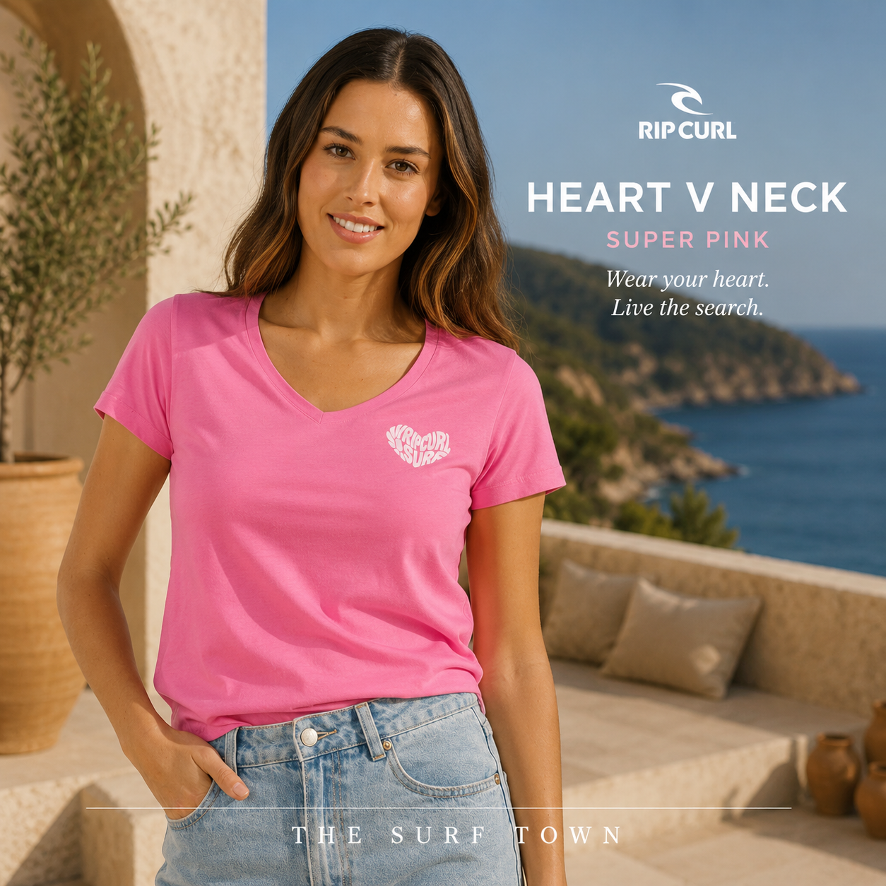 Camiseta Rip Curl Heart V Neck Super Pink para mujer en fotografía editorial propia de THE SURF TOWN sobre terraza mediterránea frente al mar, camiseta rosa con cuello pico, estilo surf femenino para verano, playa, vacaciones y lifestyle coastal premium.