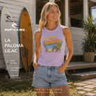 Fotografía propia de THE SURF TOWN de la camiseta Rip Curl La Paloma Lilac para mujer en una surf house australiana con tablas de surf, jardín costero y ambiente surf lifestyle premium.