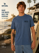 Camiseta Rip Curl Sportline FB Bluefin para hombre en escena surf lifestyle cinema aesthetic junto a playa y furgoneta surf