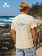 Camiseta Rip Curl Staple Tee Lemon Yellow hombre con estampado trasero surf en escenario lifestyle costero premium