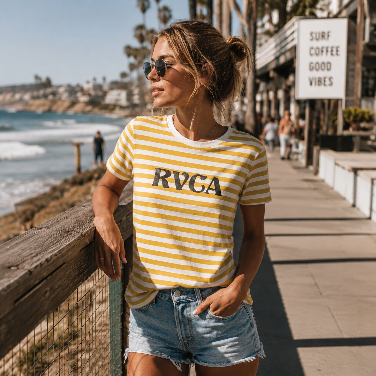 Camiseta de mujer RVCA Murphy Stripe Vintage White en fotografía editorial propia de THE SURF TOWN, camiseta de rayas amarillas estilo surf lifestyle premium en paseo marítimo costero