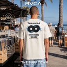 Hombre con camiseta RVCA The Magician Antique White en un mercado de vinilos junto al mar, imagen editorial propia de THE SURF TOWN