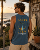 Camiseta de tirantes hombre Salty Crew azul Tailed Tank en entorno surf shack premium al atardecer frente al mar Costa del Sol