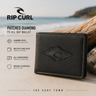 Cartera Rip Curl Patched Diamond PU All Day Wallet Black en fotografía editorial propia de THE SURF TOWN sobre fondo costero premium con diseño compacto, compartimentos para tarjetas y estilo surf masculino.