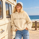 Modelo con polar sherpa Billabong Ready To Go blanco para mujer, media cremallera y logotipo bordado, vista frontal en una imagen editorial propia de the surf town en la playa junto a una furgoneta