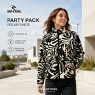 Mujer con forro polar Rip Curl Party Pack Zip Through negro y crudo en una plaza urbana, imagen editorial propia de THE SURF TOWN