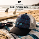 Gorra Billabong Burleigh Black Trucker Boy en fotografía editorial propia de THE SURF TOWN sobre toalla de playa junto al mar, diseño tribal en tonos azul y negro con estilo surf lifestyle para vacaciones.