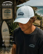 Gorra Oxbow Elini Surfspray blanca en escenario coastal premium con estética editorial surf cinematográfica