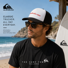 Gorra Quiksilver Omni Trucker White en fotografía editorial propia de THE SURF TOWN junto al mar con estilo surf lifestyle premium y luz natural diurna