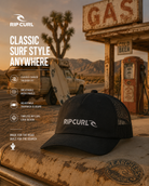 Gorra Rip Curl Trucker Brand Icons Black en gasolinera vintage del desierto con estética surf roadtrip cinematográfica