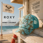 Gorra Roxy Honey Coconut Oil Green The Mo Mini RG en fotografía editorial propia de THE SURF TOWN junto a caseta de socorrista surfera, gorra floral turquesa para playa, vacaciones y estilo beach lifestyle femenino.