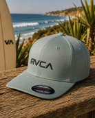 Gorra RVCA Flex Fit verde claro para hombre en escena coastal frente al mar