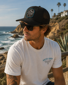Gorra Salty Crew Baited Retro Trucker Black en ambiente surf lifestyle junto al mar con estilo Costa del Sol y beach vibes premium