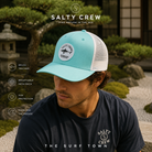 Gorra Salty Crew Bruce Trucker Turquoise en jardín japonés minimal premium, fotografía editorial propia de THE SURF TOWN con estilo surf lifestyle, parche bordado frontal y rejilla transpirable para verano