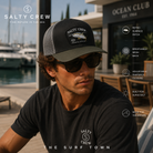 Gorra Salty Crew Surface Retro Trucker Black en club náutico contemporáneo, fotografía editorial propia de THE SURF TOWN con estilo surf lifestyle premium, parche retro de pesca deportiva y rejilla transpirable