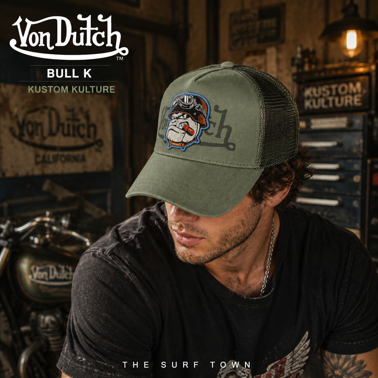 Gorra Von Dutch Bull K verde militar con bulldog bordado y rejilla trasera en fotografía editorial propia de THE SURF TOWN ambientada en un taller custom vintage inspirado en la cultura motera californiana y el estilo trucker americano.