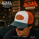 Gorra Von Dutch Cas2 Sum Hun White blanca, azul petróleo y naranja con rejilla trasera en fotografía editorial propia de THE SURF TOWN ambientada en un diner garage americano inspirado en la cultura custom californiana y el estilo trucker vintage.