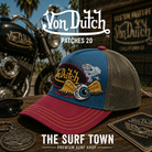 Gorra Von Dutch Patches 20 en una fotografía editorial exclusiva creada por THE SURF TOWN con estética café racer, moto custom y luz natural diurna, destacando los bordados multicolor, el diseño trucker premium y el parche frontal Von Dutch.