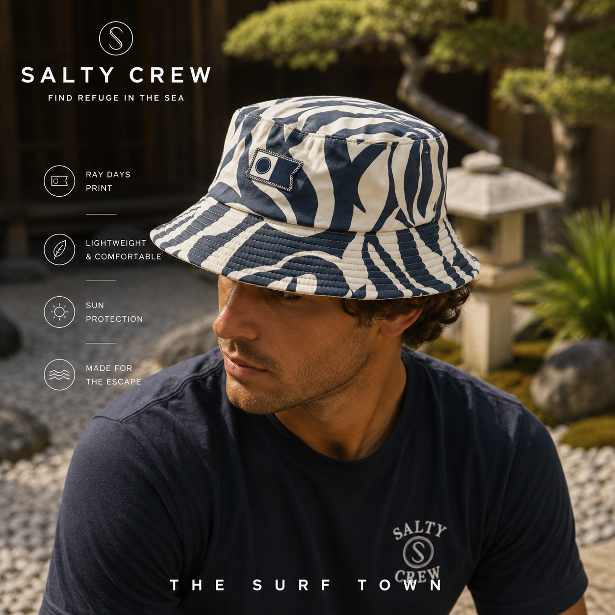 Gorro Salty Crew Ray Days Visor Indigo en jardín japonés minimal premium, fotografía editorial propia de THE SURF TOWN con modelo masculino lifestyle, estampado azul índigo y protección solar para verano