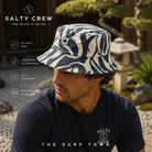 Gorro Salty Crew Ray Days Visor Indigo en jardín japonés minimal premium, fotografía editorial propia de THE SURF TOWN con modelo masculino lifestyle, estampado azul índigo y protección solar para verano