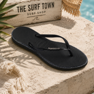 Chancla Havaianas Slim Glitter negra para mujer en escenario beach lifestyle mediterráneo premium