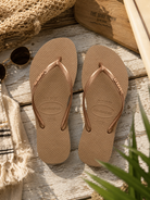 Chanclas Havaianas Slim Logo Metallic Gold para mujer en ambiente beach lifestyle premium de THE SURF TOWN