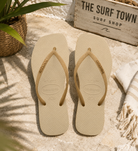 Chanclas Havaianas Slim Square Sparkle color sand grey para mujer en escenario beach club mediterráneo premium