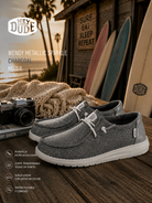 Zapatillas Hey Dude Wendy Metallic Sparkle Charcoal para mujer en escenario surf lifestyle premium con estética coastal cinema y luz dorada editorial