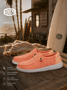 Zapatillas Hey Dude Wendy Sox Peach para mujer en escenario surf lifestyle premium junto al mar con estética coastal cinema y luz cálida editorial