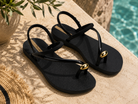Sandalias Ipanema Glam Ring negras con detalle dorado en terraza mediterránea junto a piscina premium