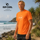 Licra Rip Curl Stapler Mandarin Red en fotografía editorial propia de THE SURF TOWN junto a olas y costa tropical en surf trip premium