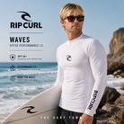 Licra Rip Curl Waves UPF50 Performance White LS para hombre en fotografía editorial propia de THE SURF TOWN junto al mar con protección solar UPF 50+, manga larga y diseño surf performance para playa y deportes acuáticos.